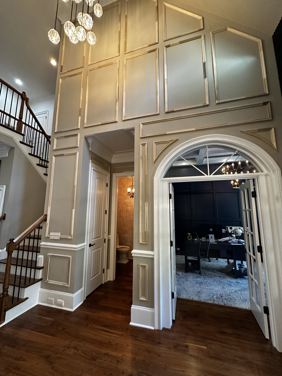 Tall foyer wall with rectangular molding surrounding the arched office doorway