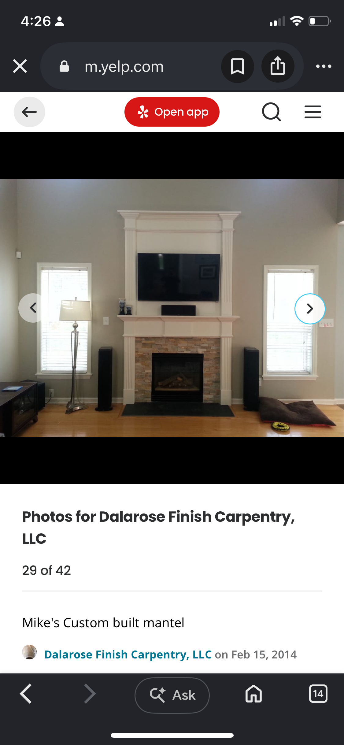 Custom white fireplace mantel and tall paneled surround framing a television above a stone fireplace