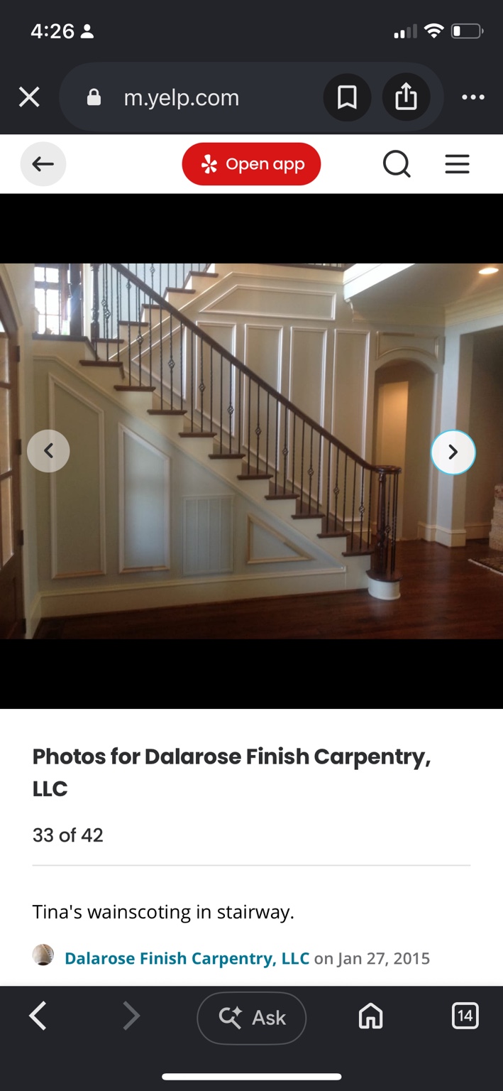 Stairway with white geometric wainscoting following the slope beneath dark wood and iron railings