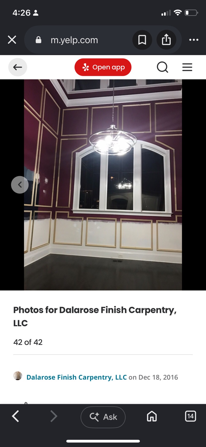 Burgundy two-story room with wood picture-frame molding surrounding an arched window, before painting